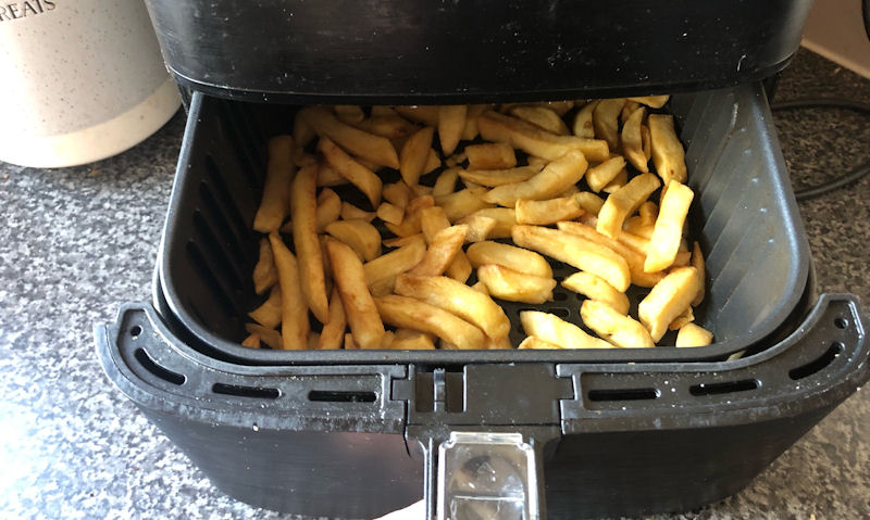 Air fryer basket slid out to reveal golden chippy chips