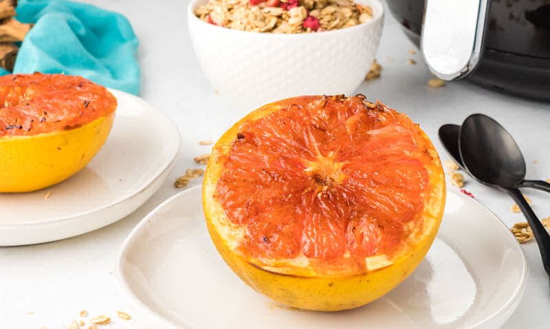 Air fried red grapefruit next to white air fryer on counter