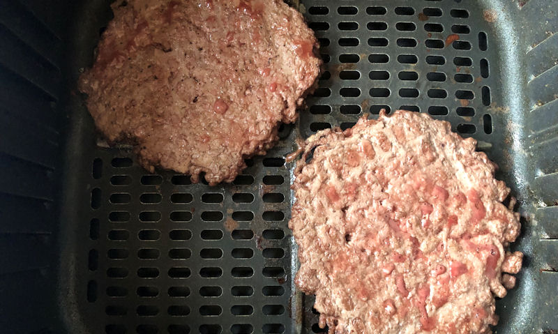 Fresh partially cooked smash beef patties in air fryer basket