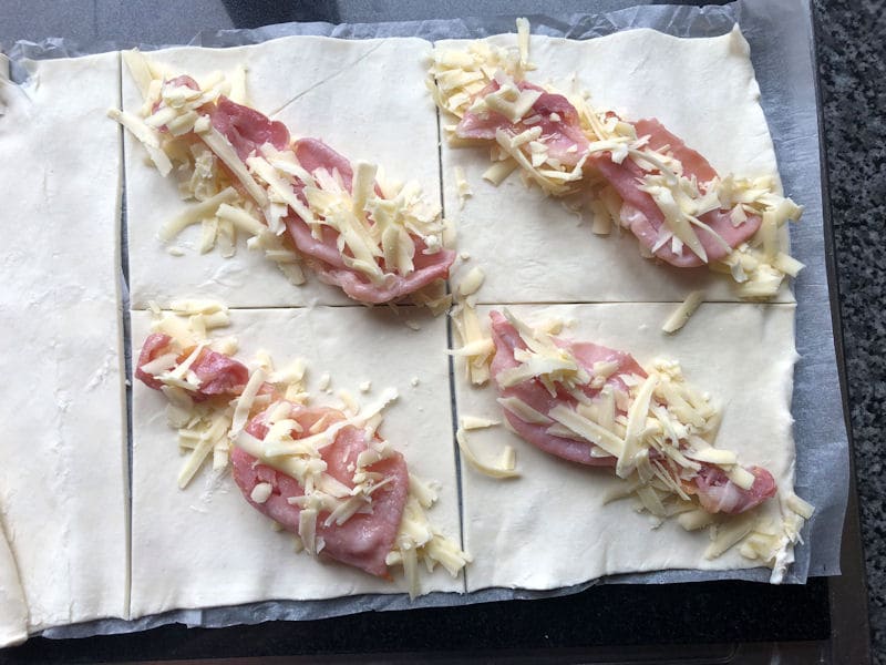 Bacon, grated cheese on top of pastry from corner to corner