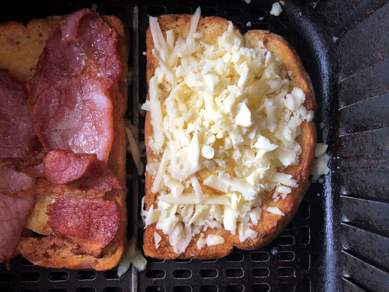 Freshly grated cheese sprinkled over partially cooked egg on bread slice