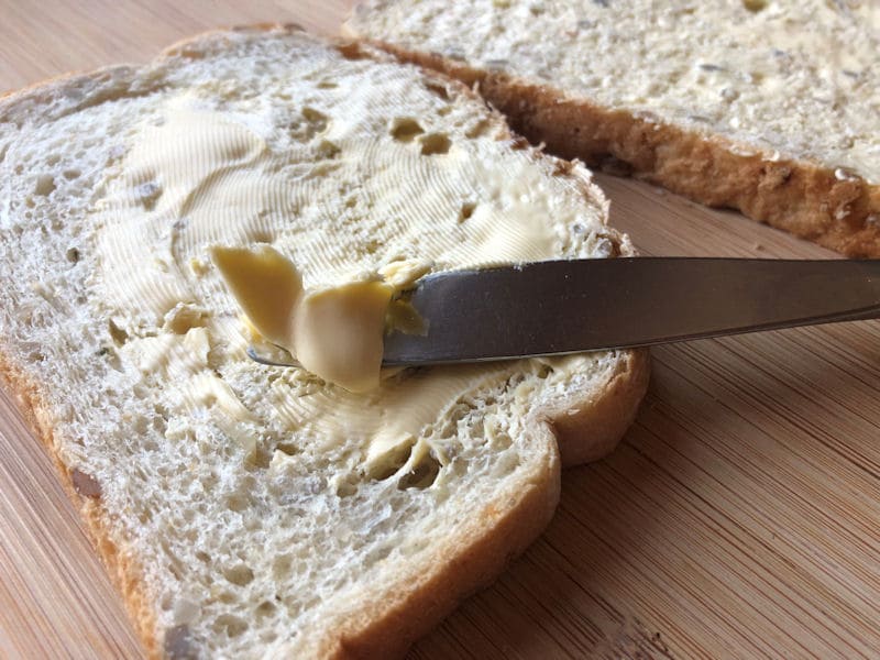 Spreading butter onto two slices of seeded bread