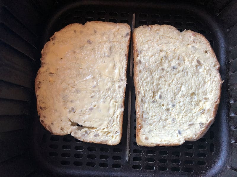 Slices of seeded bread side by side in air fryer basket