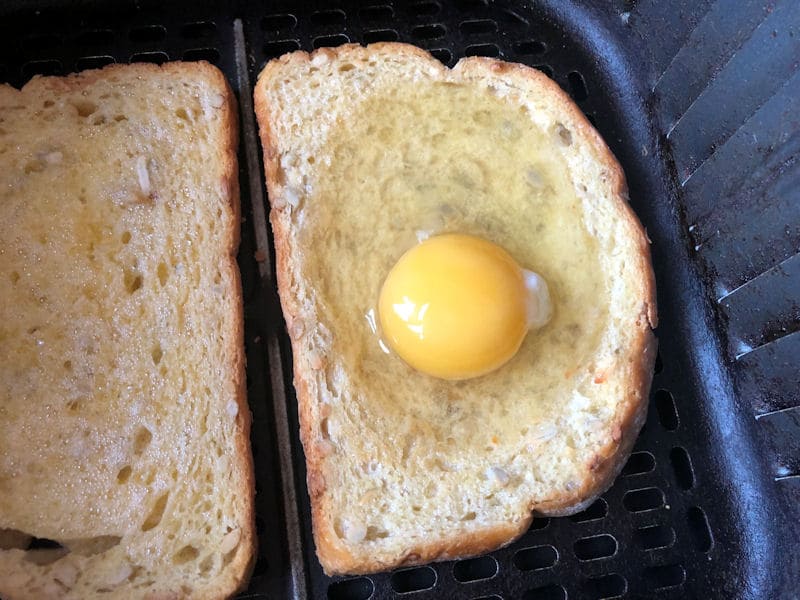 Raw egg poured onto bread slice with indent