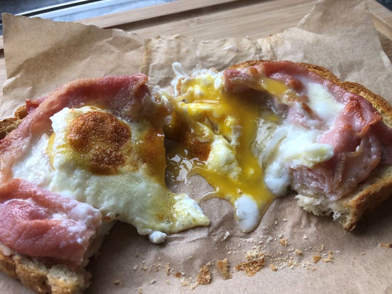 Runny yolk pouring out of cooked bacon and egg toast