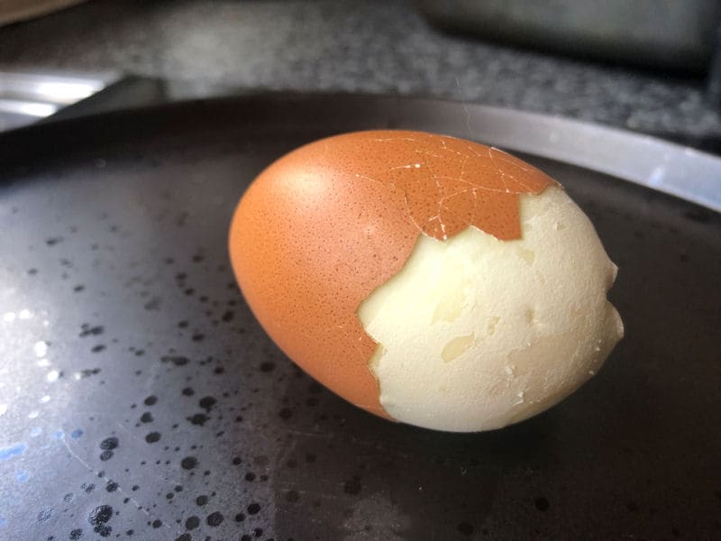 Partially cracked open air fried hard boil egg on dinner plate