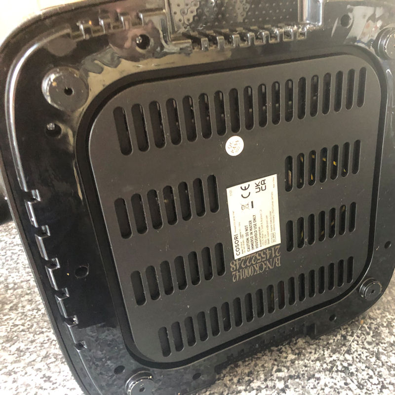 Air fryer tipped on side to inspect bottom of appliance