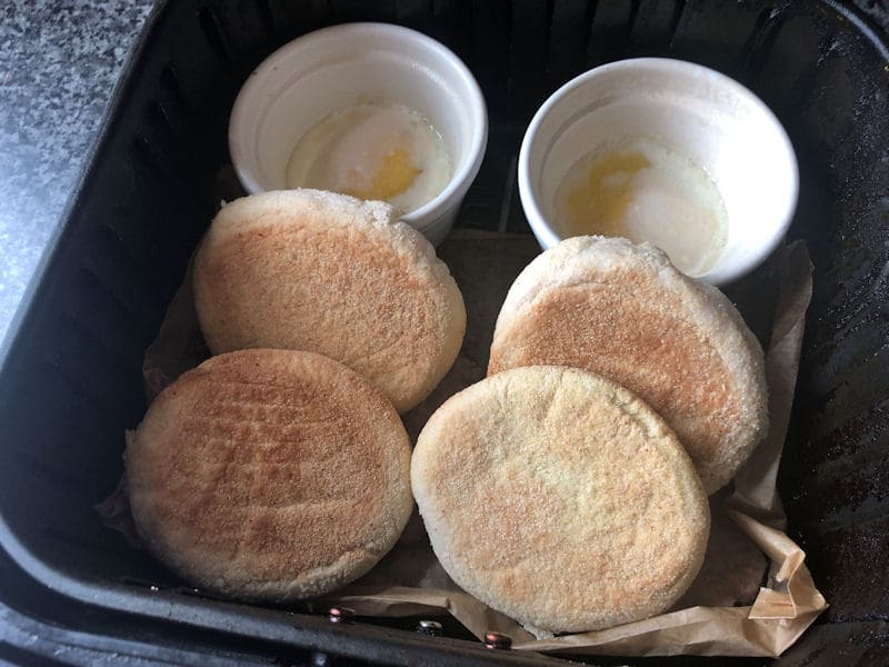 English muffin halves positioned against ramekins inside air fryer