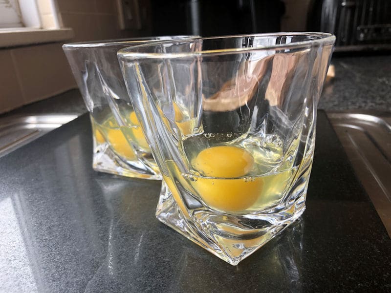 Raw eggs cracked into individual drinking glasses