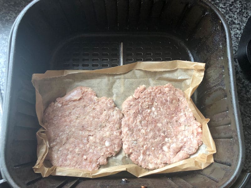 Sausage patties positioned on baking paper, on one side of basket