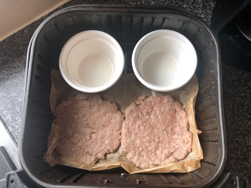 Row of two ramekins with two sausage patties inside air fryer