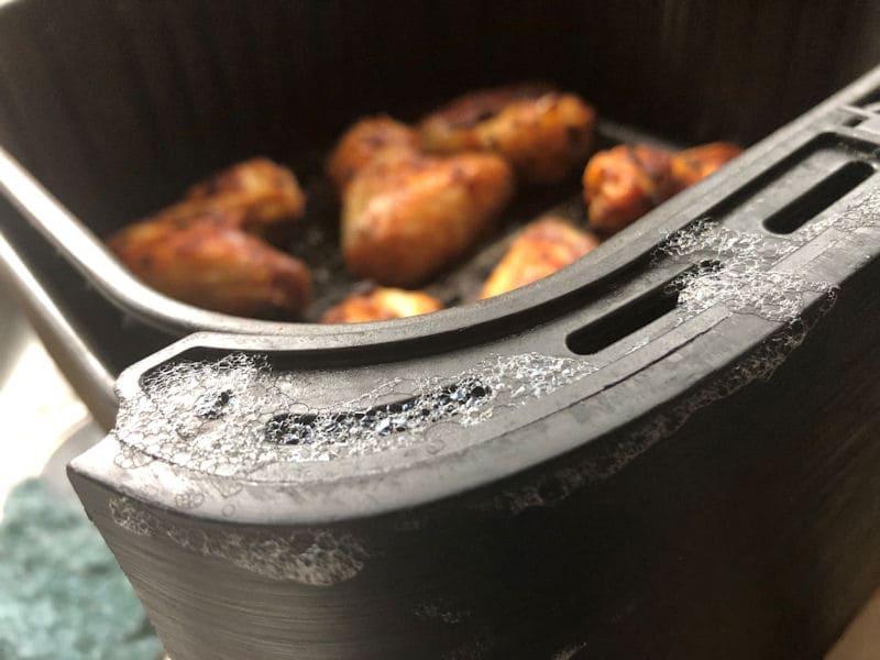 Soapy bubbles resting on rim of air fryer basket