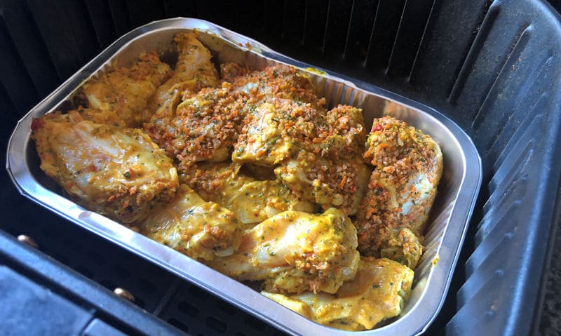 Raw mango and coconut loaded chicken wings in foil tray in air fryer