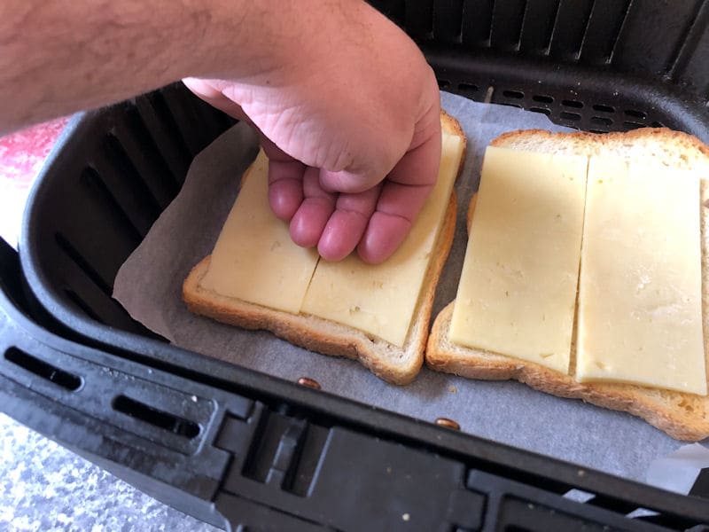 Pressing slices of cheese into toast using back of hand