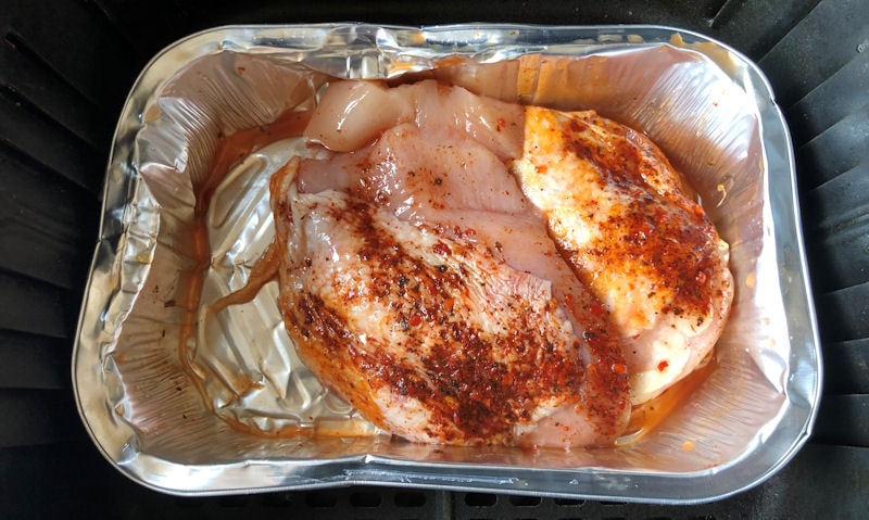 Raw chicken breasts in foil tray, sat in air fryer basket