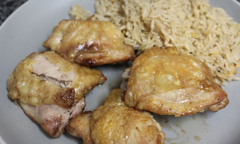 Plate of four crispy chicken thighs served with microwave egg fried rice