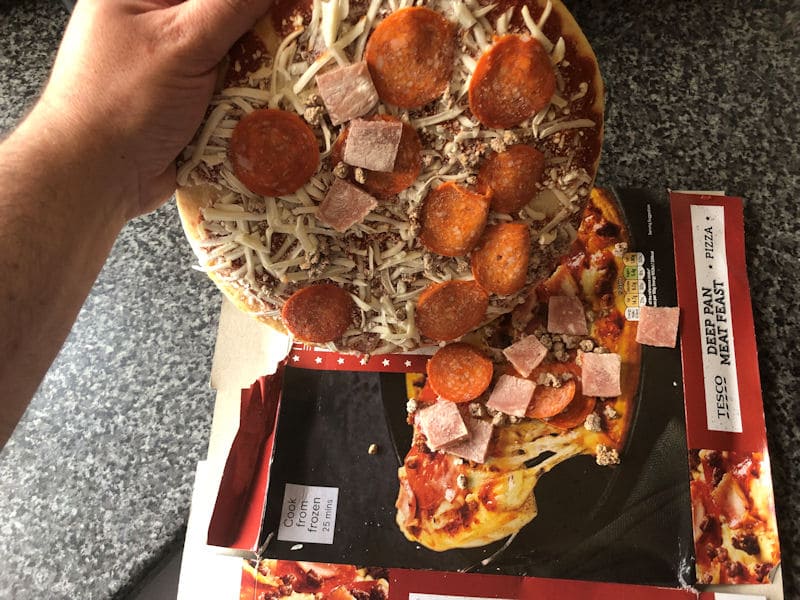 Loose frozen pizza toppings brushed onto pizza box