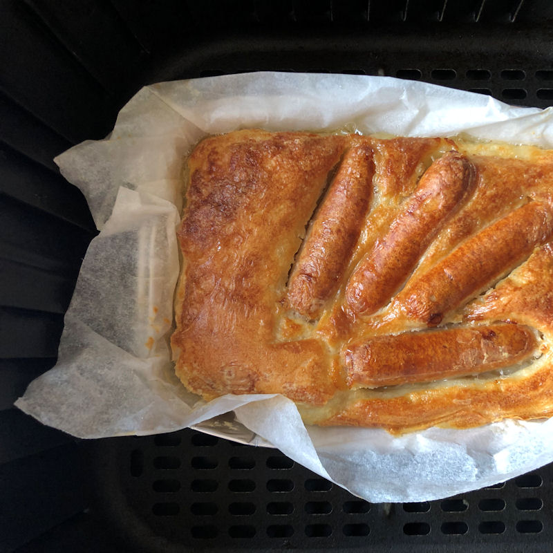 Toad in the hole placed in parchment paper lined foil tray in air fryer