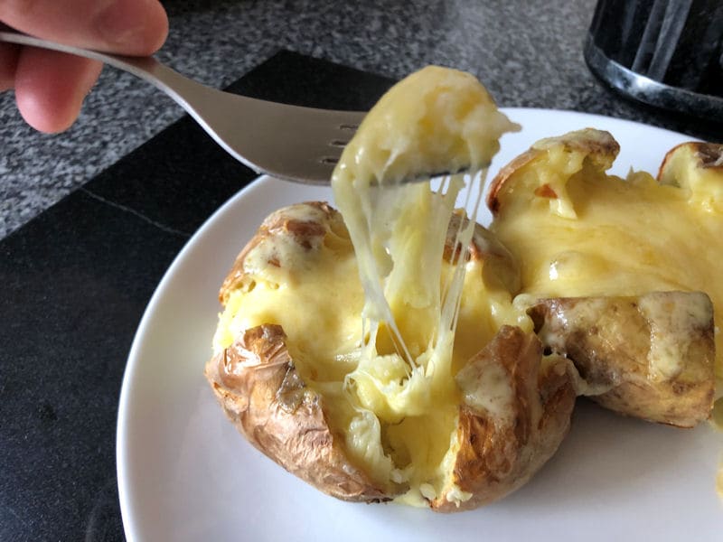 Fork used to pick up soft jacket potato mash with melted cheese