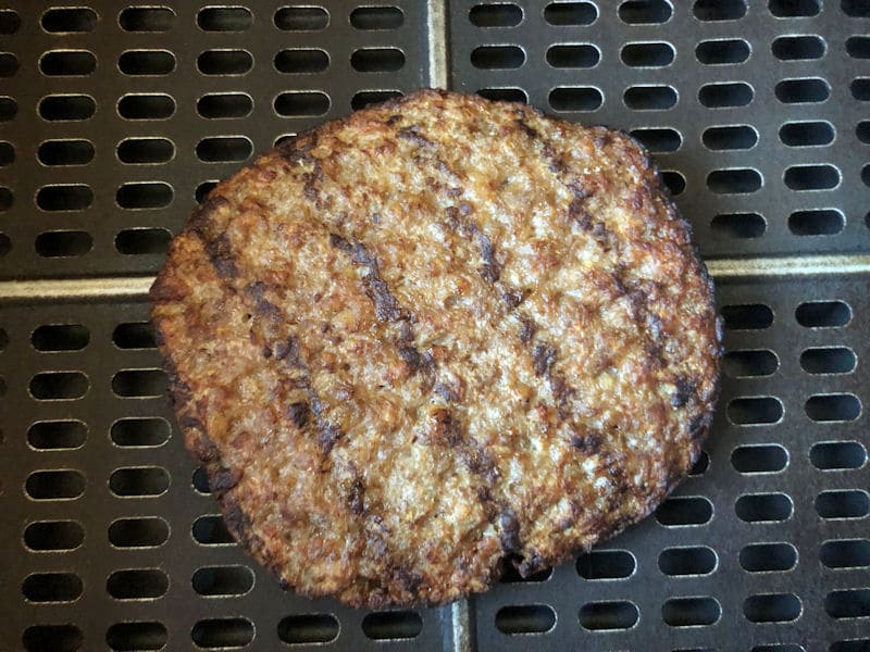 Cooked microwave burger patty sat directly on air fryer basket