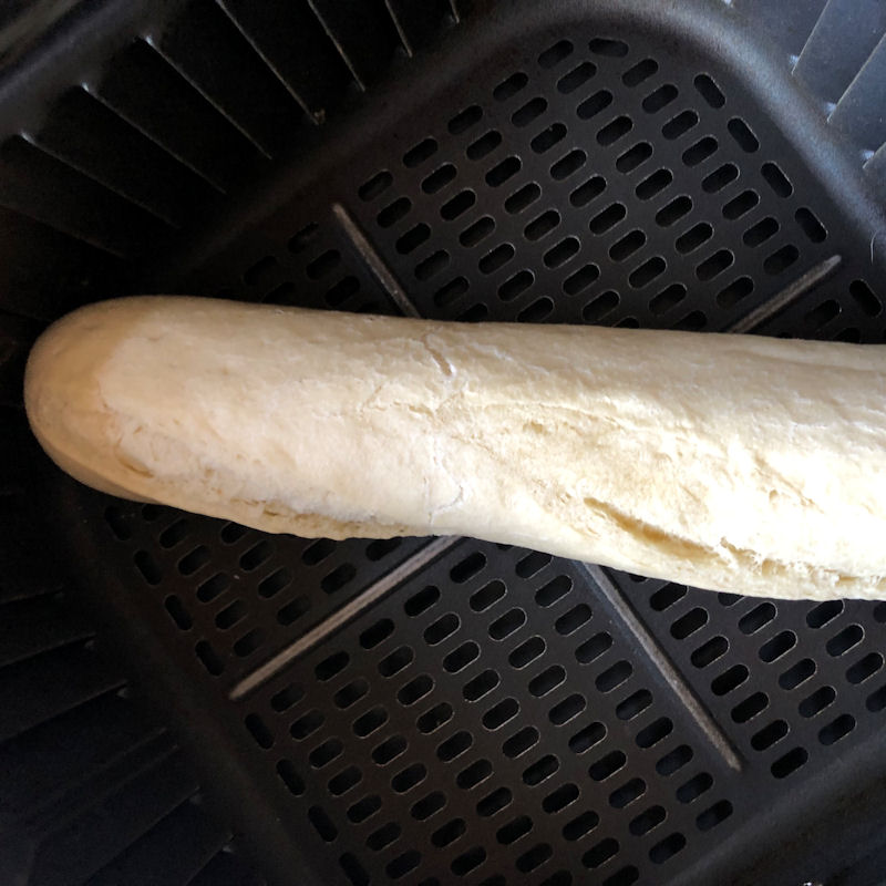 Part baked baguette positioned in air fryer basket corner to corner