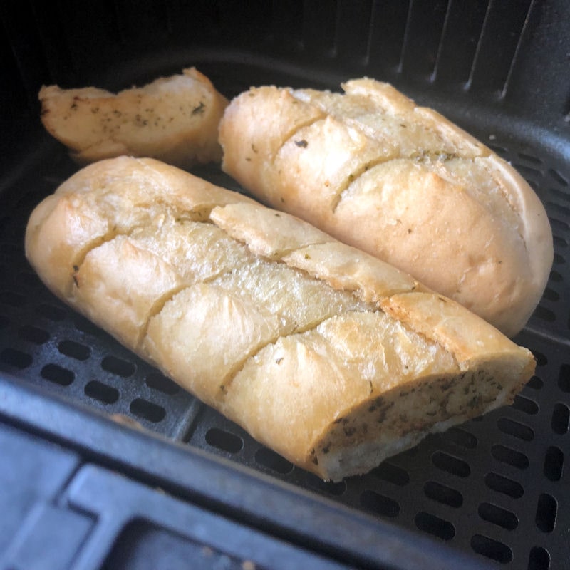 Cut up garlic baguette positioned in air fryer basket