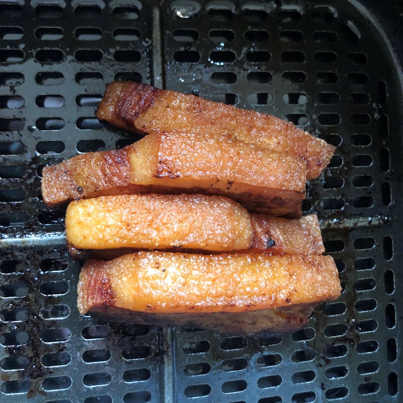 Group of four pork belly slices sitting in center of air fryer basket