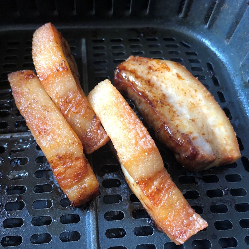 Pork belly slices standing in basket; one slice tipped over