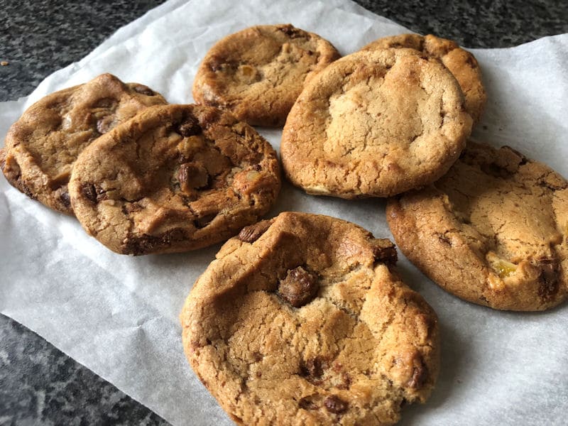 Pile of freshly air fried chocolate and orange cookies piled on baking paper