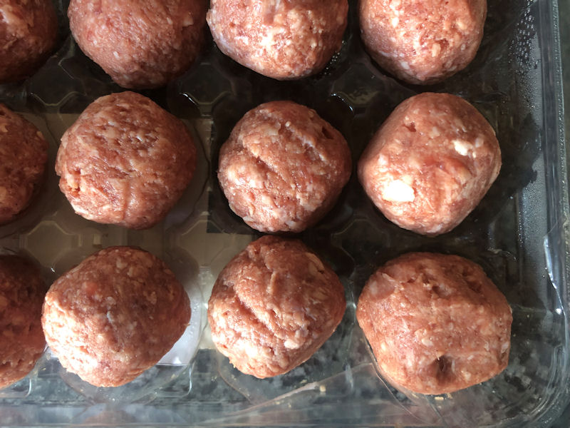 Same size raw beef meatballs in plastic packaging