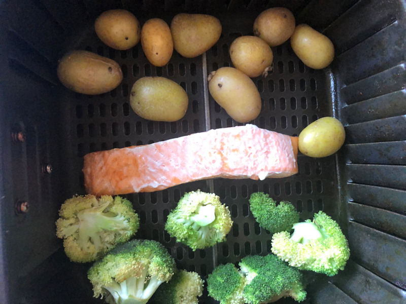 Salmon situated in between portion of broccoli and small potatoes