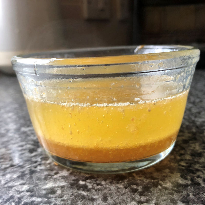 Glass bowl of basting chicken juices and cooking oil