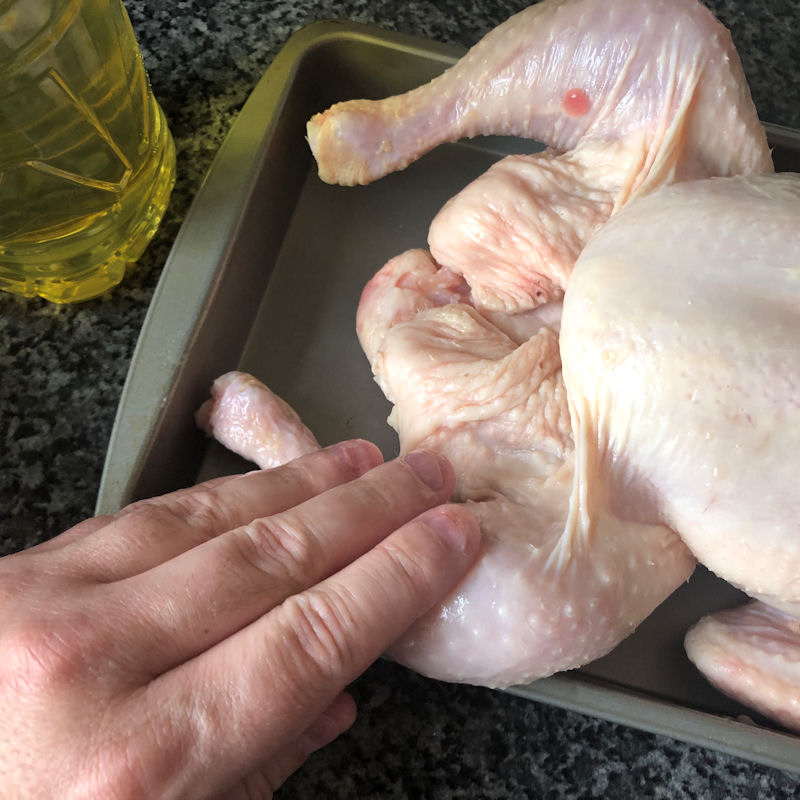 Rubbing vegetable oil into leg of a whole small chicken