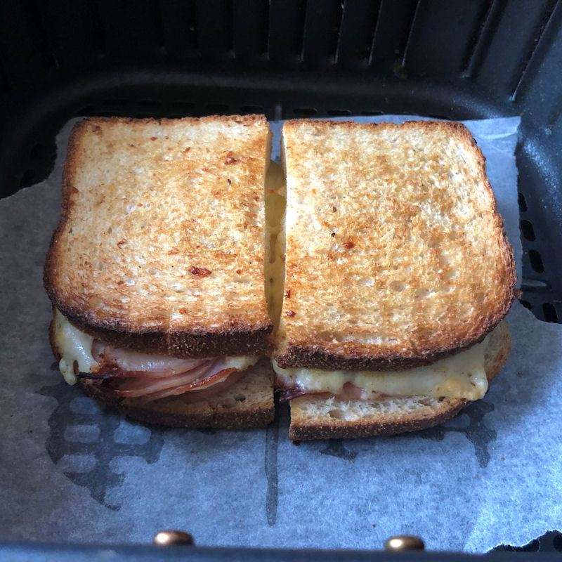 Toastie halves coming apart sitting on parchment paper in air fryer