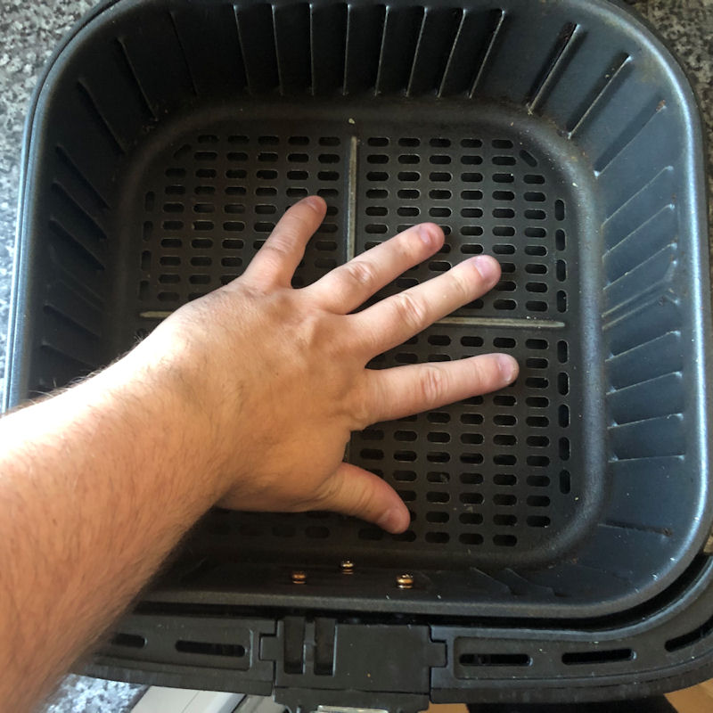 My hand placed in bottom of 5.5 liter Cosori basket for scale