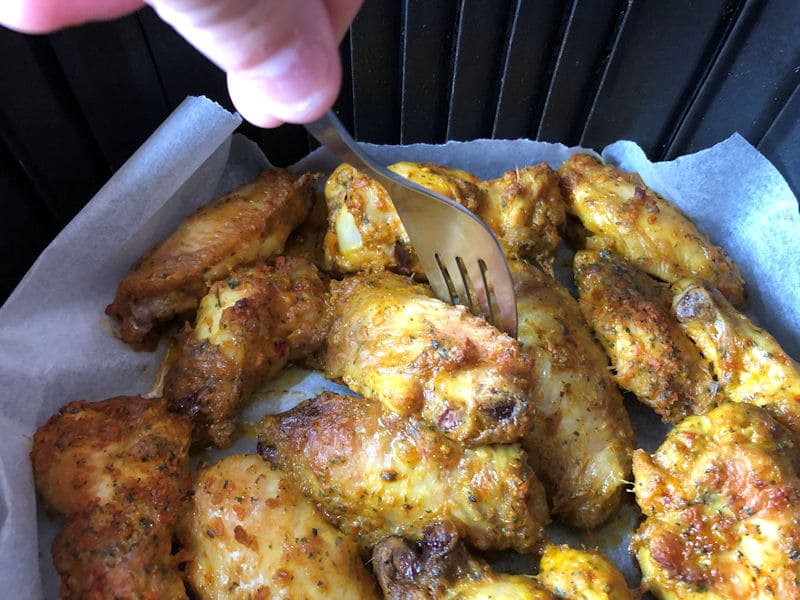 Marinated chicken wings air fried on white parchment paper in air fryer basket