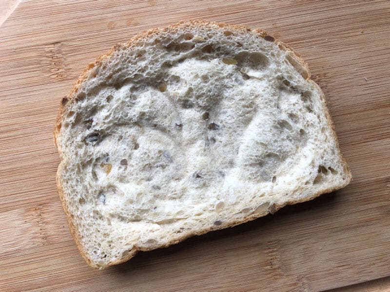 Bread slice on chopping board, with drinking glass imprint on surface