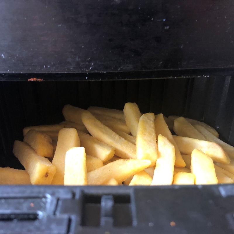 Oven fries filled high in partially opened air fryer basket