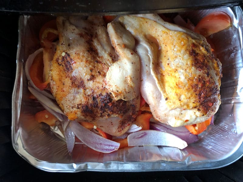 Piri Piri chicken breasts over peppers and onion in foil tray