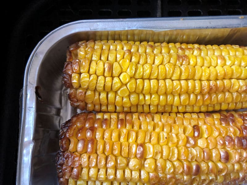 Charred Corn on the Cobs inside air fryer, in reusable foil tray