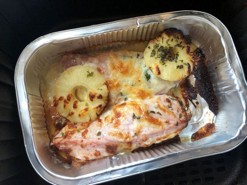 Cooked gammon steaks with pineapple rings and melted cheese in foil tray