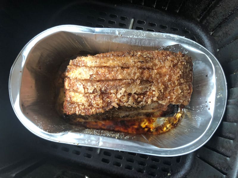 Pork loin joint air fried in foil tray positioned in air fryer