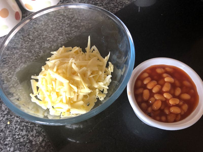 Glass dish of grated cheese, ramekin of cold baked beans