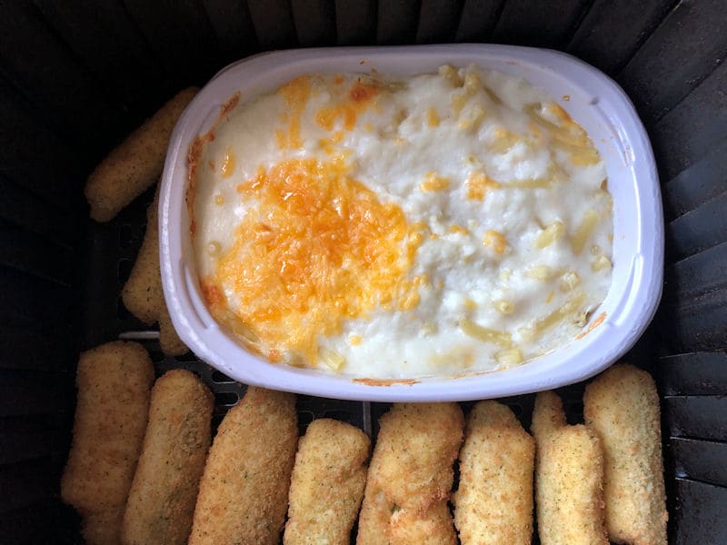 Frozen mac and cheese air frying alongside fresh jalapeno peppers bites