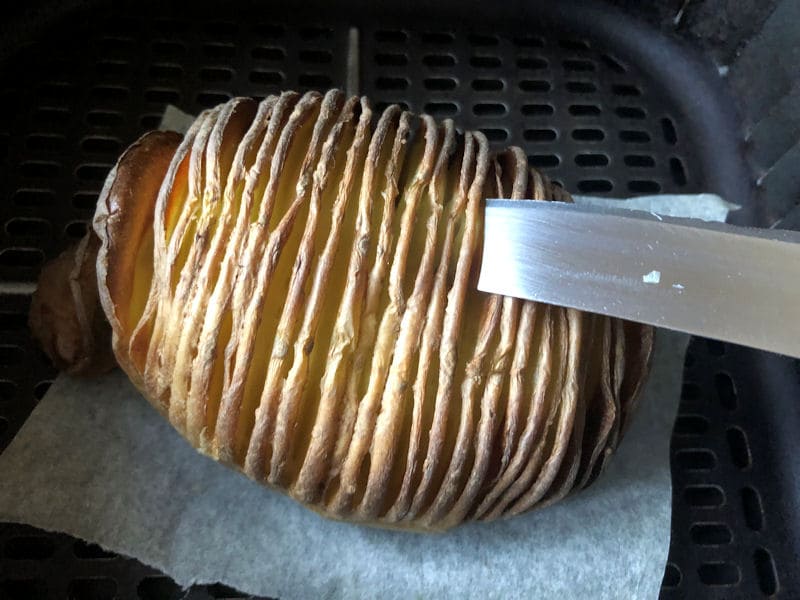 Knife impaled into fully cooked Hasselback potato