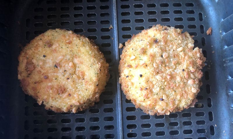 Pair of breaded Salmon fish cakes positioned in air fryer basket