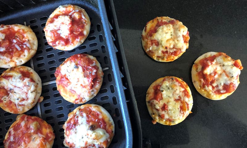 Mini pizzas in air fryer basket; mini pizzas on granite chopping board