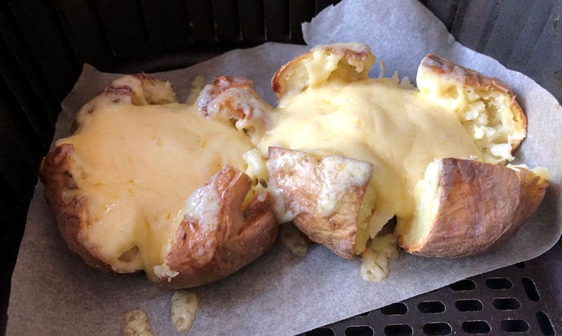 Melted cheese-topped jacket potatoes in air fryer basket