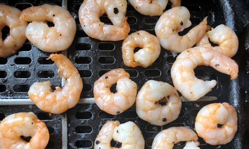 Loose, cooked raw peeled King Prawns in air fryer basket