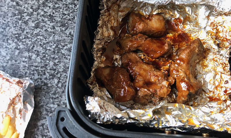 Ready to eat BBQ ribs sitting on foil in air fryer basket